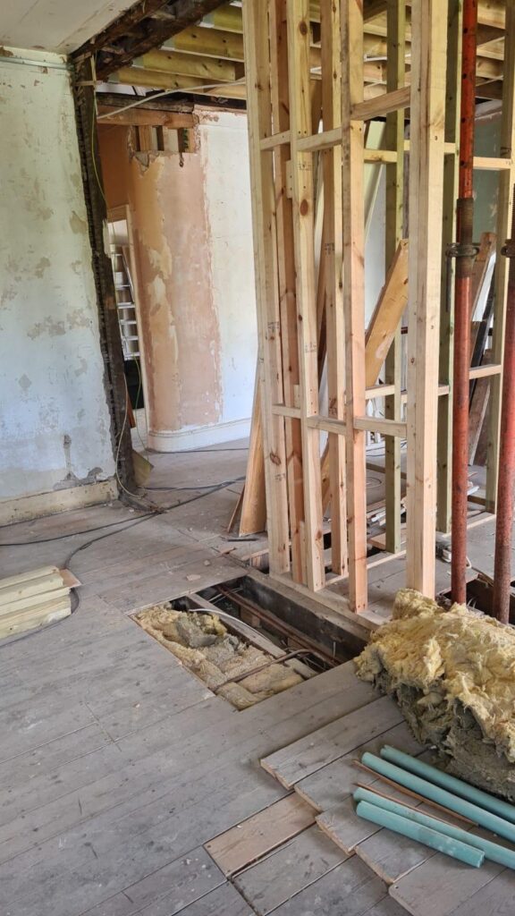 Room during a load-bearing wall removal, with timber studwork and a steel support prop in place